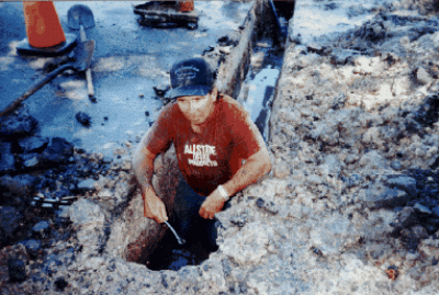Man in a red shirt digging in a hole